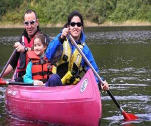 Puzle Família, pai, mãe e filha, vela e remando em uma canoa, equipados com coletes salva-vidas