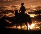 Cowboy ou vaqueiro cavalgando ao entardecer ou