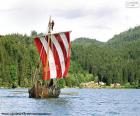 Drakkar ou navio viking ou viquingue com todos os remadores em ação e a vela inchada com o vento