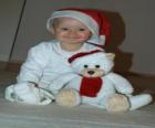 Menino com um chapéu de Papai Noel com seu ursinho de pelúcia