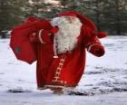 Papai Noel carregando o grande saco de presentes de Natal no mato