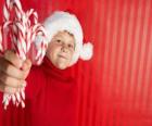 Criança com chapéu de Papai Noel e bastões de doces na mão