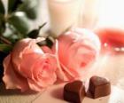 Duas rosas cor de rosa com dois coração em forma de chocolates