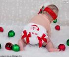 Um bebê muito Natal, com uma fralda de Papai Noel e várias bolas coloridas