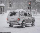 Um carro a passar por uma cidade totalmente nevada no inverno