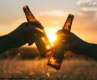 Dois amigos brinde com duas cervejas durante um belo pôr do sol