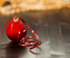 Bela foto de uma bola de Natal vermelha com uma fita vermelha para pendurar na árvore